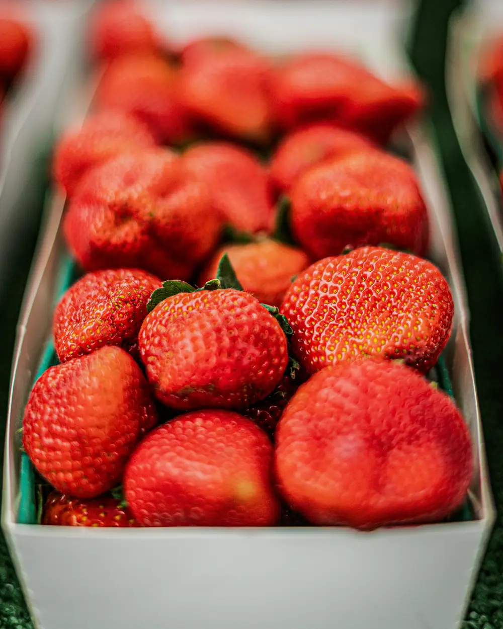 A carton of ripe strawberries at a market stand